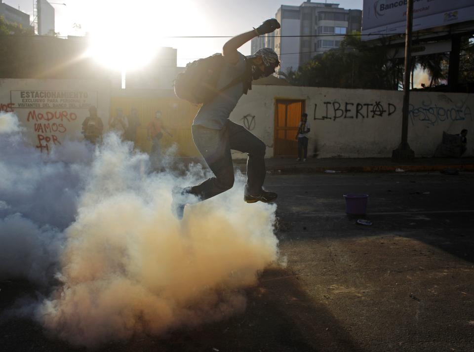 Anti-government protester jumps over tear gas during a rally in Caracas