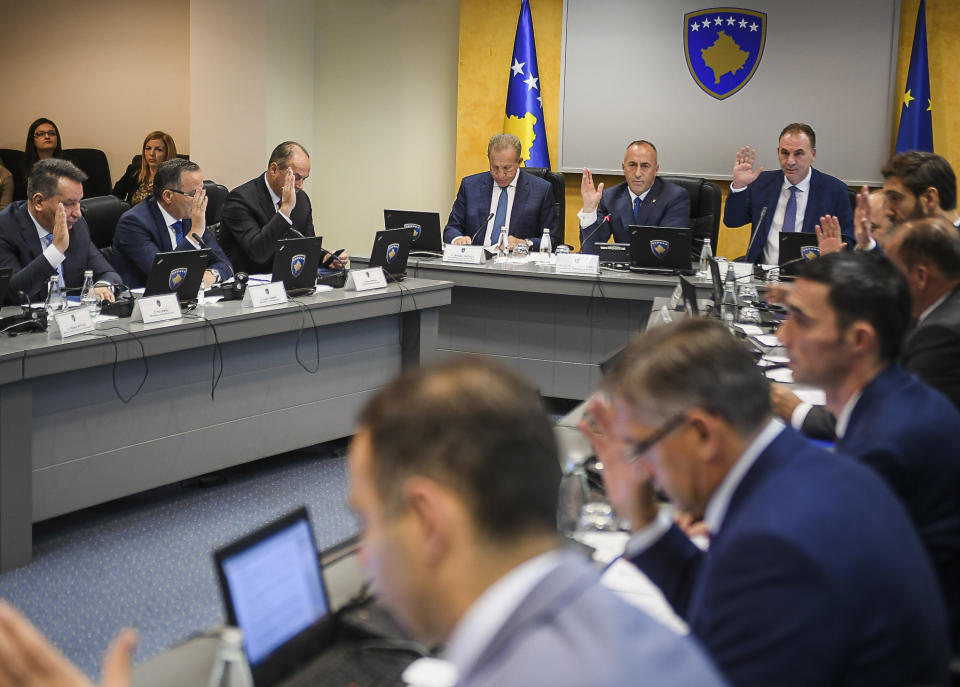 In this photo provided by the Kosovo government public affairs office, showing Kosovo Prime Minister Ramush Haradinaj, center back, with his cabinet voting during the government meeting on Wednesday, Nov. 21, 2018, in Kosovo capital Pristina. Kosovo's government has decided to introduce a 100 percent import tax on all goods imported from Serbia and Bosnia Herzegovina. (Kosovo Government via AP)