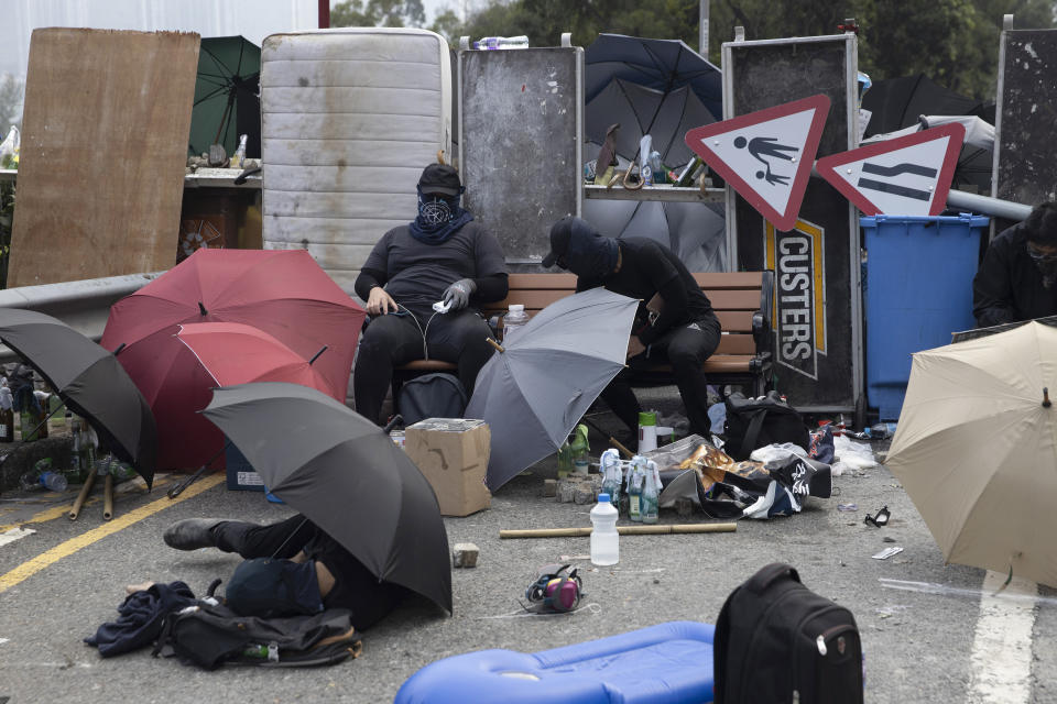 Pro-democracy protesters take rest near barricades set on a bridge outside the Chinese University campus in Hong Kong, Wednesday, Nov. 13, 2019. Police increased security around Hong Kong and its university campuses as they brace for more violence after sharp clashes overnight with anti-government protesters. (AP Photo/Ng Han Guan)