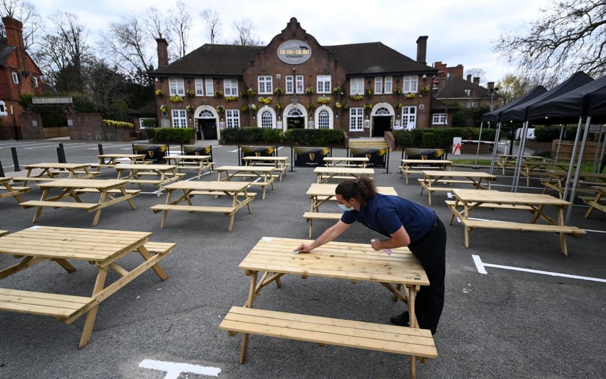 A worker at a London pub with a large outdoor area prepares tables ahead of Monday's reopening - Andy Rain/EPA-EFE/Shutterstock