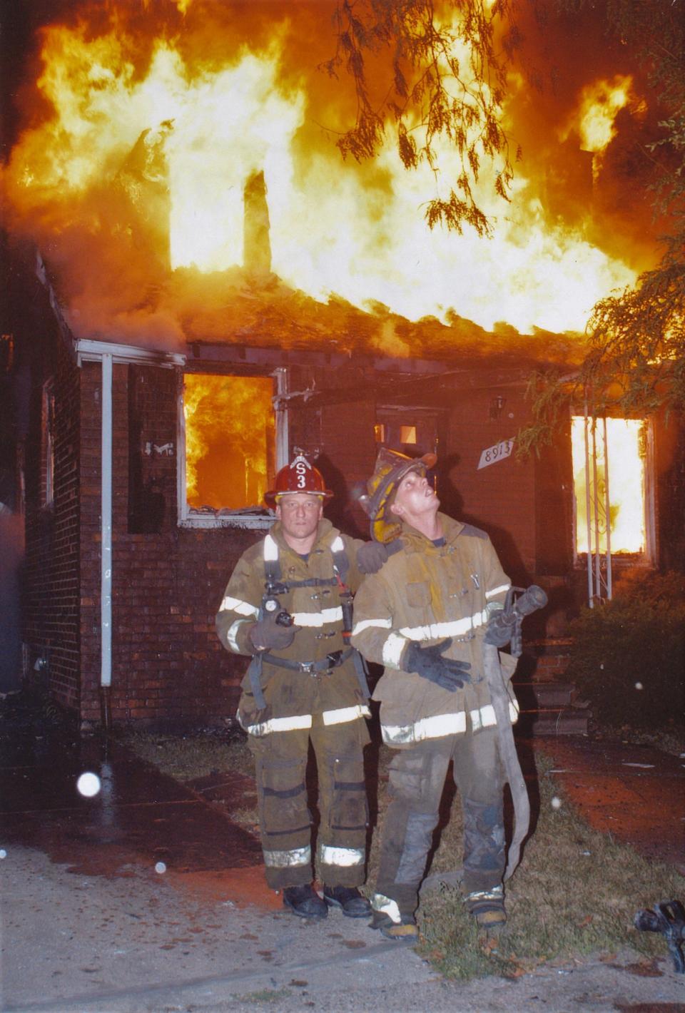From left, Detroit firefighter Mike Nevin, at the time ranked sergeant, lays his hand on the shoulder of an unidentified young firefighter to calm a rookie while the two waited to receive water for dousing a serious house fire in Detroit in 2010-2015.