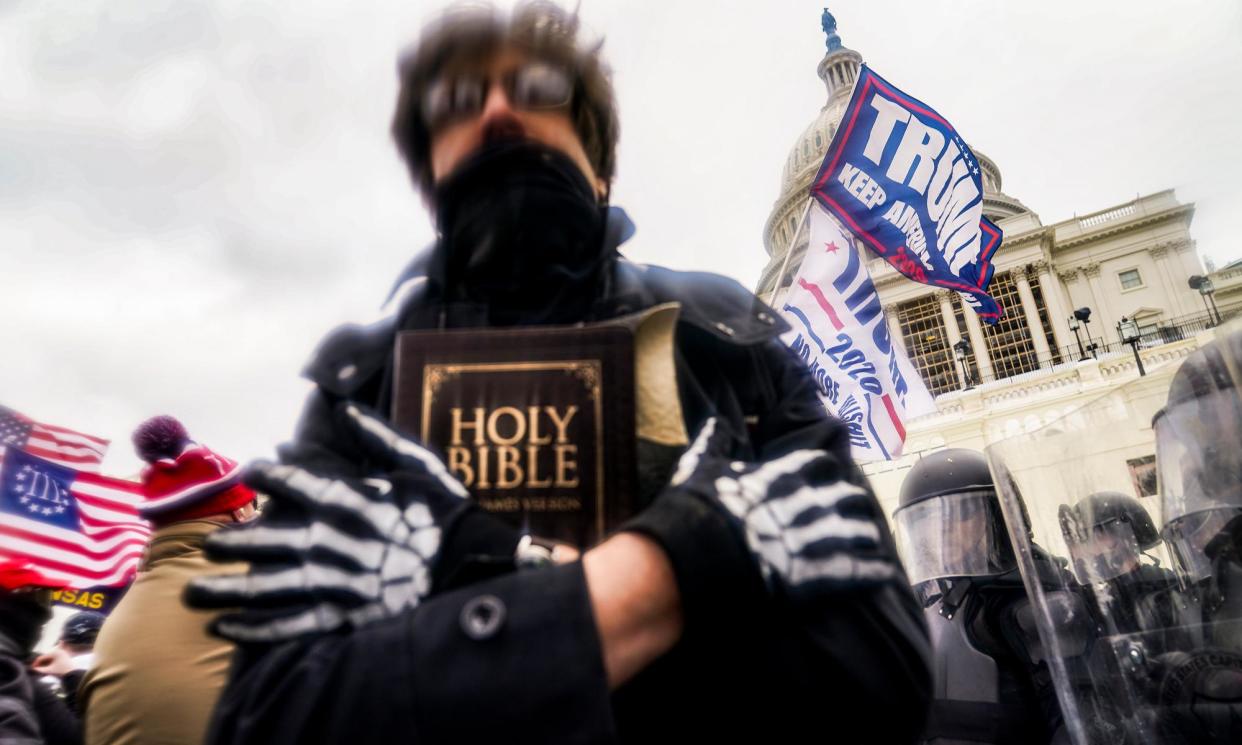 <span>A man holds a Bible as Trump supporters gather outside the Capitol in Washington on 6 January 2021.</span><span>Photograph: John Minchillo/AP</span>