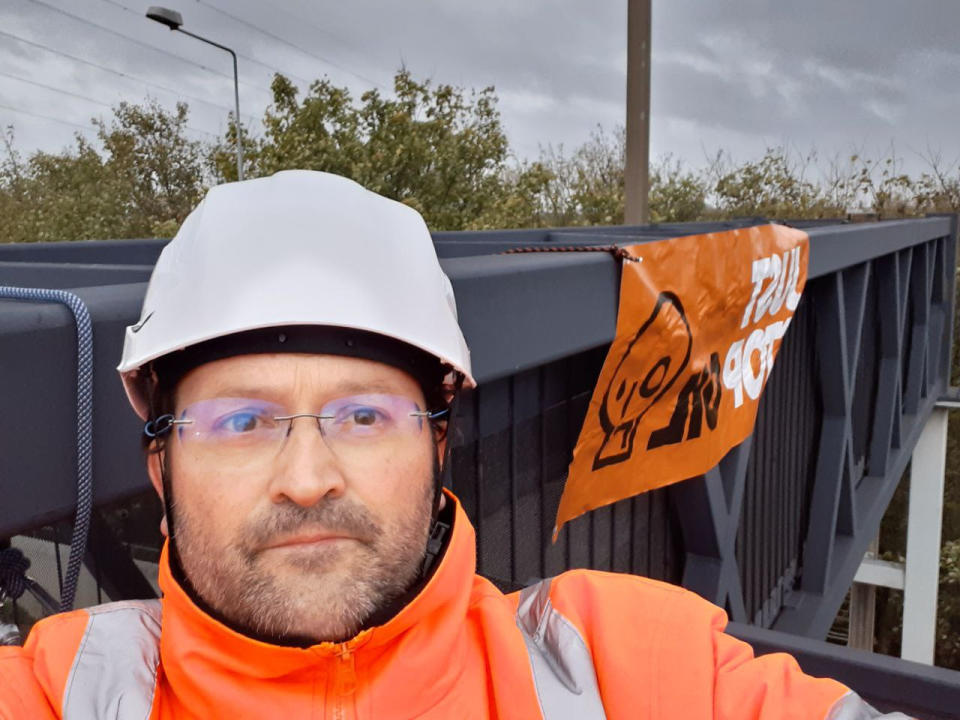 Handout photo issued by Just Stop Oil of a protester who has climbed a gantry on the M25 between junctions six and seven in Surrey, leading to the closure of the motorway. Surrey Police said the decision was made to close the road 