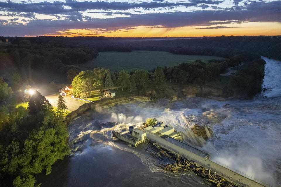 This long-exposure drone photo provided by AW Aerial shows a home as it teeters before partially collapsing into the Blue Earth River at the Rapidan Dam in Rapidan, Minn., Tuesday, June 25, 2024. (Andrew Weinzierl/AW Aerial via AP)