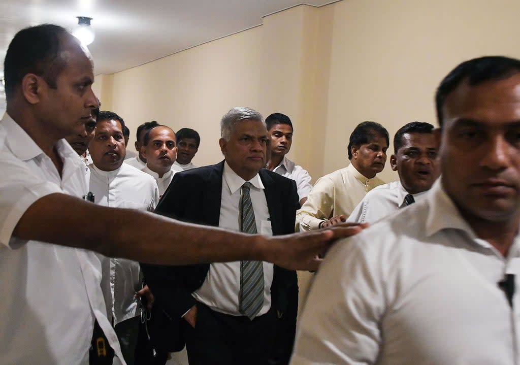 Sri Lankan prime minister Ranil Wickremesinghe (Centre) leaves parliament escorted by security personnel and aides in Colombo  (AFP via Getty)