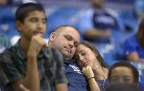 FILE - In this Sept. 21, 2013, file photo, two Tampa Bay Rays fans sleep in the stands during the 16th inning of a baseball game against the Baltimore Orioles in St. Petersburg, Fla. Major League Baseball will start each extra inning this season by putting a runner on second base. MLB is experimenting with the rule this year in part to prevent marathon games from causing long-term damage to pitching staffs in a pandemic-shortened season. (AP Photo/Phelan M. Ebenhack, File)