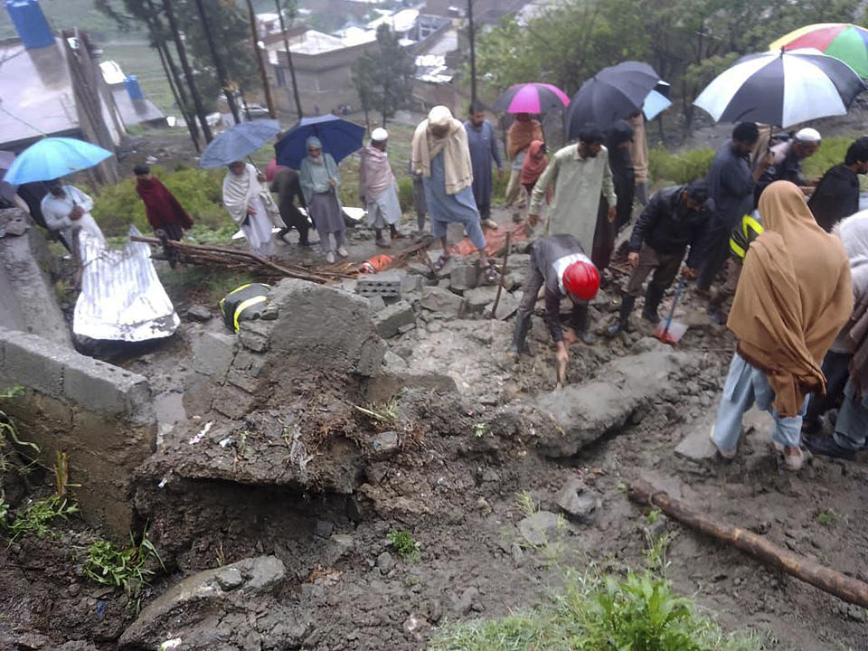 In this photo provided by the Rescue 1122 Emergency Department, rescue workers and locals gather to clear the rubble of a house partially damaged by landslide due to heavy rainfall in Matta, a town in Swat Valley, Pakistan, Sunday, April 14, 2024. Lightening and heavy rains killed dozens of people, mostly farmers, across Pakistan in the past three days, officials said Monday, as authorities declared a state of emergency in the country's southwest following an overnight rainfall to avoid any further casualties and damages. (Rescue 1122 Emergency Department via AP)