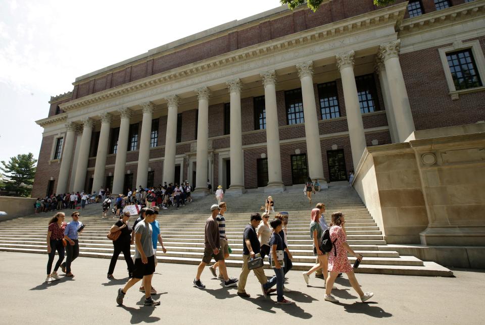 People walk past an entrance to Widener Library, behind, on the campus of Harvard University, in Cambridge, Massachusetts on July 16, 2019.