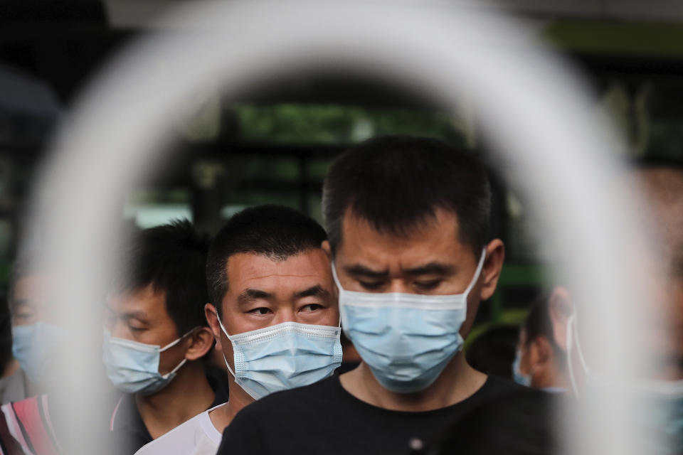 Commuters wearing protective face masks to help curb the spread of the new coronavirus line up to board a bus at a bus terminal in Beijing, Monday, June 22, 2020. A Beijing government spokesperson said the city has contained the momentum of a recent coronavirus outbreak that has infected a few hundreds of people, after the number of daily new cases fell to single digits. (AP Photo/Andy Wong)