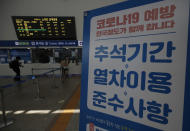 Passengers arrive to buy train tickets near a banner reading "Notice to use the train during the Chuseok holiday. Prevention of COVID-19" at the Seoul Railway Station in Seoul, South Korea, Monday, Sept. 28, 2020. The coronavirus is forcing South Koreans to celebrate their Thanksgiving holiday differently this year. Health authorities are discouraging travel during the five-day Chuseok autumn holidays that begin Wednesday, Sept. 30, 2020 because of concern that people could spread the virus. (AP Photo/Lee Jin-man)