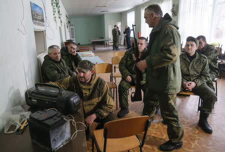 Pro-Russian rebels adjust the radio as they prepare to listen to Russian President Vladimir Putin's annual end-of-year news conference broadcast in Donetsk, December 18, 2014. REUTERS/Maxim Shemetov