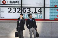 People stand in front of an electronic stock board of a securities firm in Tokyo, Tuesday, Dec. 3, 2019. Asian shares slipped Tuesday, following a drop on Wall Street amid pessimism over U.S.-China trade tensions. (AP Photo/Koji Sasahara)