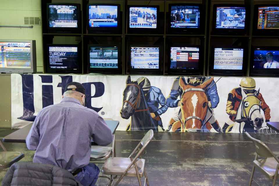 A person waits for the horses to race at Fonner Park in Grand Island, Neb., Saturday, March 14, 2020. Fonner was one of the few sporting venues in the country open to fans Saturday, unfortunately the races were called off due to dangerous track conditions following snowfall. (AP Photo/Nati Harnik)