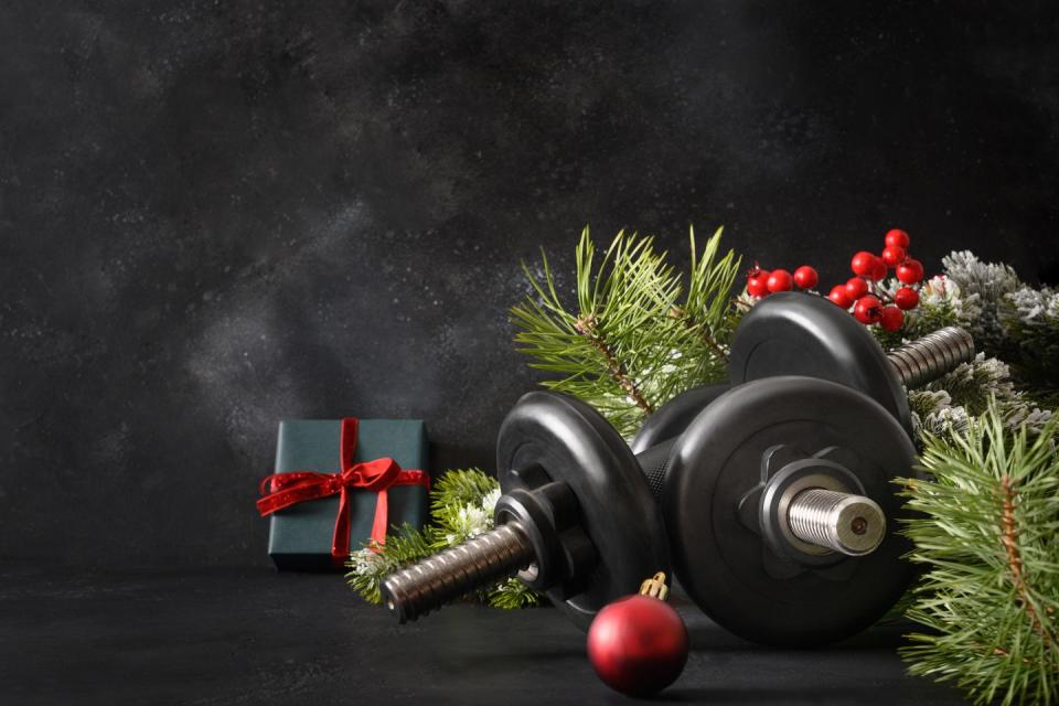 christmas sport composition with blue sports dumbbells, gift, fir tree branches and christmas gift