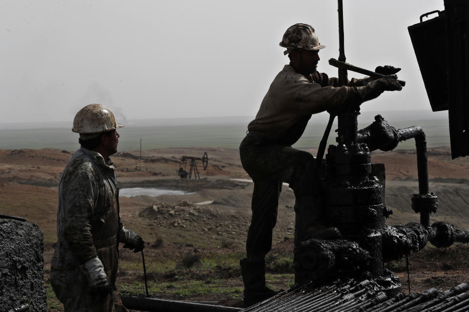 FILE - This March 27, 2018 file photo, shows Syrian workers fixing pipes of an oil well at an oil field controlled by a U.S-backed Kurdish group, in Rmeilan, Hassakeh province, Syria. President Donald Trump's decision to dispatch new U.S. forces to eastern Syria to secure oil fields is being criticized by some experts as ill-defined and ambiguous. But the residents of the area, one of the country's most remote and richest regions, hope the U.S. focus on eastern Syria would bring an economic boon and eliminate what remains of the Islamic State group. (AP Photo/Hussein Malla, File)