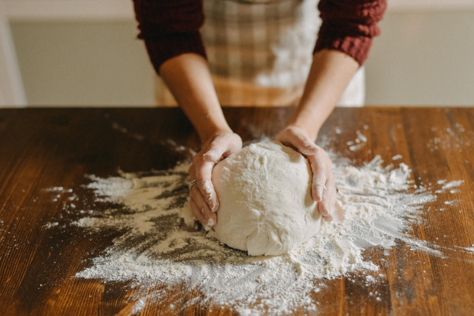 Woman kneading bread dough. Close up of her hands touching the dough.