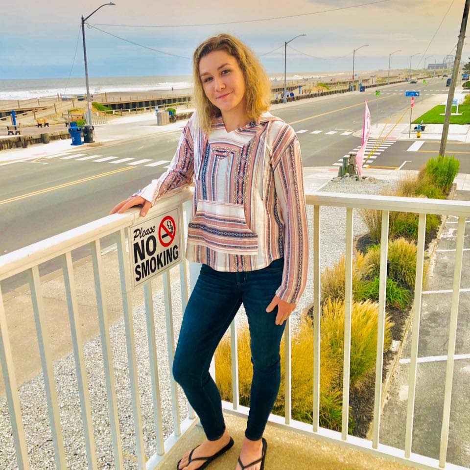 Christine Englehardt stands on a balcony in front of a beach. 