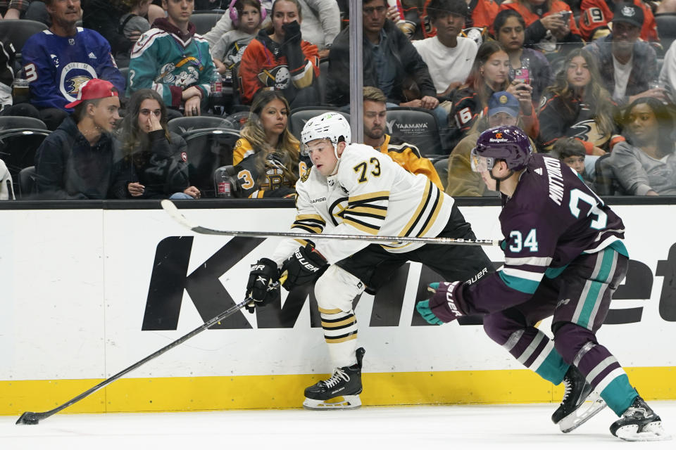 Boston Bruins defenseman Charlie McAvoy, left, controls the puck as Anaheim Ducks defenseman Pavel Mintyukov chases during the second period of an NHL hockey game Sunday, Oct. 22, 2023, in Anaheim, Calif. (AP Photo/Ryan Sun)