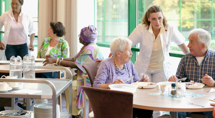 A group of senior people having lunch together in a retirement home, LTC Properties operates senior housing and living facilities