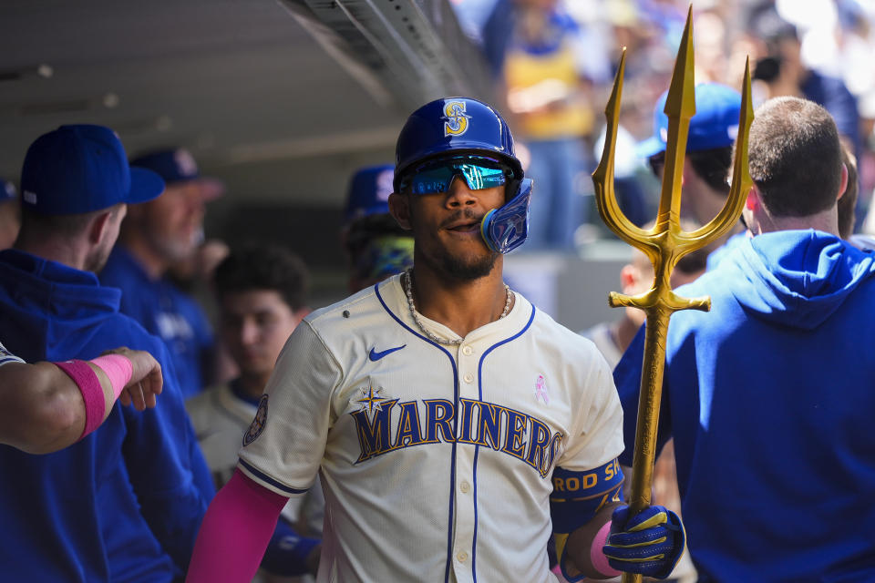 Seattle Mariners' Julio Rodríguez holds a trident in the dugout after hitting a two-run home run against the Oakland Athletics during the second inning of a baseball game Sunday, May 12, 2024, in Seattle. (AP Photo/Lindsey Wasson)