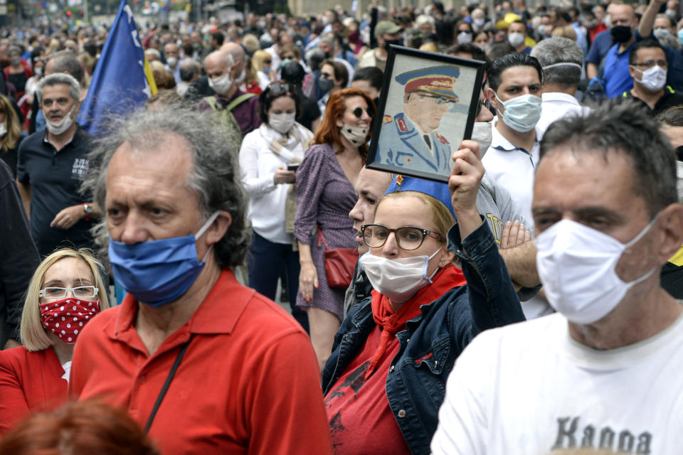 A woman holds a portrait of Yugoslav leader Josip Broz Tito, as people attend an anti-Nazi protest outside the Sacred Heart Cathedral during a mass commemorating members of the pro-Nazi Croatian WWII Ustasha regime, responsible for sending tens of thousands of Serbs, Gypsies and Jews to their death in concentration camps, who were killed at the end of WWII by Yugoslav communist troops, in Sarajevo, Bosnia, Saturday, May 16, 2020. Bosnian Catholic clerics along with Croatian state representatives and members of the Bosnian Croats community attended a religious service commemorating the massacre of Croatian pro-Nazis by victorious communists at the end of World War II. (AP Photo/Kemal Softic)