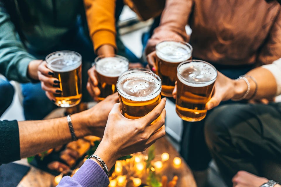  Happy multiracial people enjoying happy hour with pint sitting at bar table. (Photo via Getty Images)