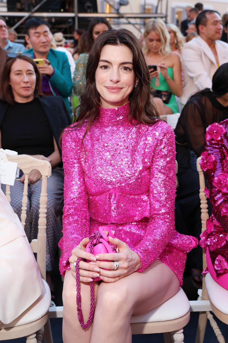 Anne Hathaway sitting front row at a fashion show in a short sequined dress