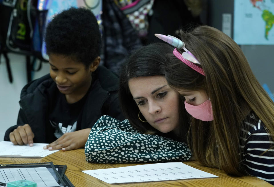 First grade teacher, Lindsey Land, center, listens to student, Emma Benn, right, as she instructs her students during classes at Chimborazo Elementary School Thursday, Nov. 17, 2022, in Richmond, Va. The Richmond school district, which includes Chimborazo elementary, ultimately decided against year-round school. (AP Photo/Steve Helber)