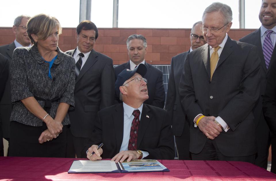 Flanked by Senate Majority Leader Harry Reid, D-Nev., right, and Bureau of Land Management state director Amy Leuders, left, Interior Secretary Ken Salazar prepares to sign a plan that sets aside 285,000 acres of public land for the development of large-scale solar power plants Friday, Oct. 12, 2012, in Las Vegas. The plan replaces the department’s previous first-come, first-served system of approving solar projects, which let developers choose where they wanted to build utility-scale solar sites and allowed for land speculation. (AP Photo/Julie Jacobson)