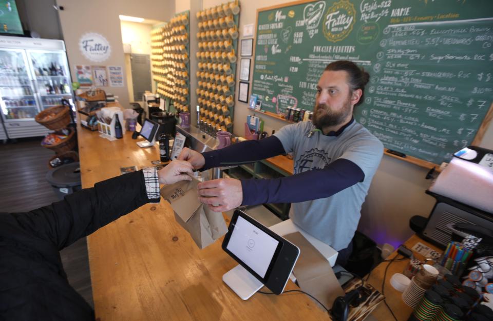 Jeff Baumann, co-owner, hands a purchase to a customer at Fattey Beer Company, in the new Neighborhood of Play in Rochester Monday, Oct. 16, 2023.