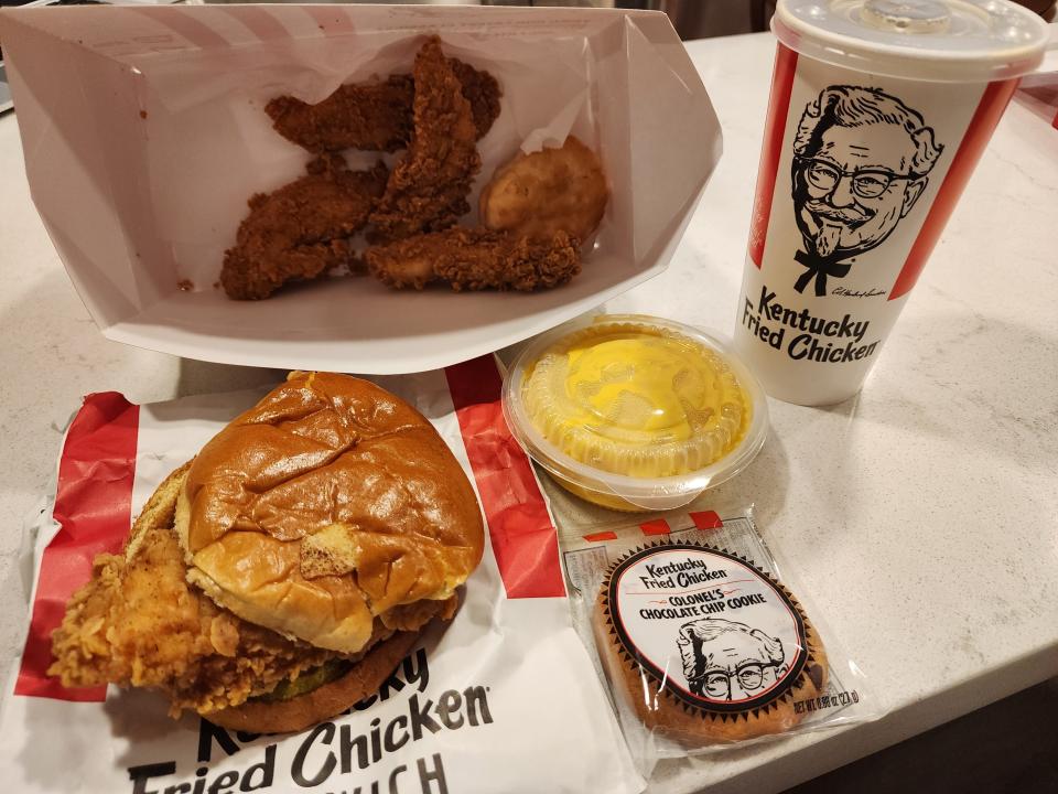 KFC meal with chicken sandwich, chicken tenders, mac and cheese, a cookie, and soda