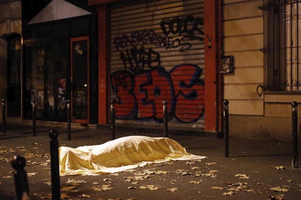 FILE - A victim under a blanket lays dead outside the Bataclan theater in Paris, Nov. 13, 2015. The historic trial in Paris of 20 men suspected of critical roles in the Islamic State massacres that killed 130 people in 2015 has ended this week with verdicts against the defendants in France's worst peacetime attack expected on Wednesday June 29. (AP Photo/Jerome Delay, File)