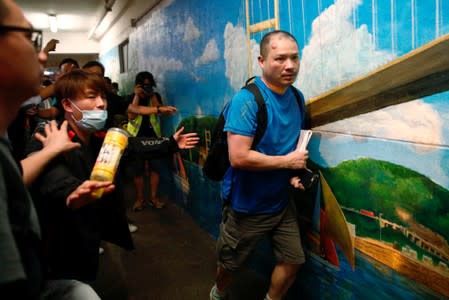 People create a passageway for a pro-government supporter to leave after he was beaten up by anti-extradition supporters outside the office of pro-China lawmaker Junius Ho in Tsuen Wan