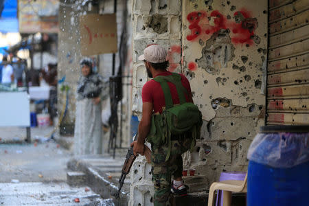 A member of the joint Palestinian security force stands in front of a bullet-riddled wall inside the Ain el-Hilweh refugee camp near Sidon, southern Lebanon, August 18, 2017. REUTERS/Ali Hashisho