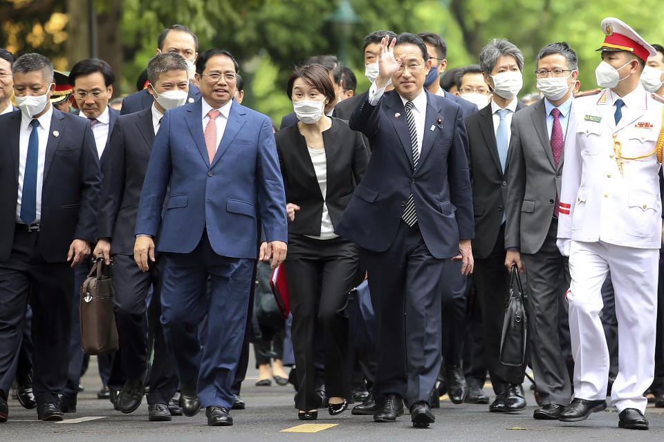 Japanese Prime Minister Fumio Kishida, center right, and Vietnamese Prime Minister Pham Minh Chinh, center left, walk in the Presidential Palace in Hanoi, Vietnam on Sunday, May 1, 2022. (AP Photo/Hoang Minh)