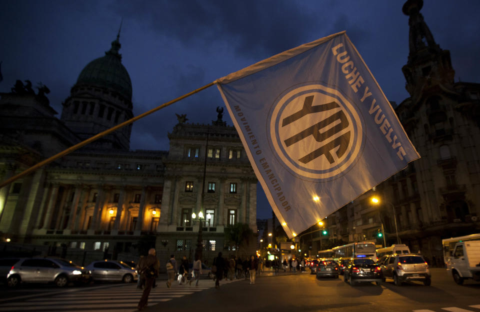 A supporters of an oil nationalization bill proposed by Argentina's President Cristina Fernandez holds a flag reading in Spanish "Fight and return YPF" outside the National Congress as senators debate the bill in Buenos Aires, Argentina, Wednesday, April 25, 2012. Fernandez, who pushed forward a bill to renationalize the country's largest oil company, said the legislation put to congress would give Argentina a majority stake in oil and gas company YPF by taking control of 51 percent of its shares currently held by Spain's Repsol. (AP Photo/Natacha Pisarenko)