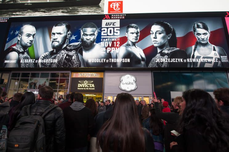 People in Times Square pass a large ad touting UFC 205, which will be Saturday at Madison Square Garden in New York. (Getty Images)