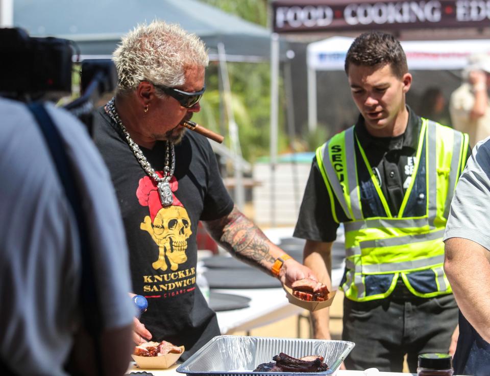 Guy Fieri grabs some barbecue to give to a security guard during the Stagecoach country music festival in Indio, Calif., Friday, April 29, 2022.