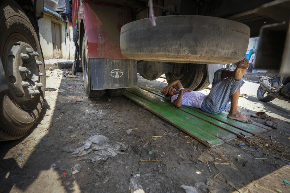 A man sleeps under a truck on a hot summer day in Guwahati, India, Saturday, May 25, 2024. (AP Photo/Anupam Nath)