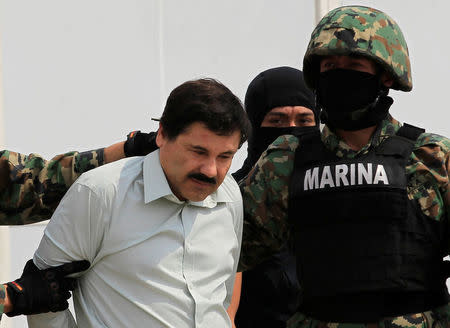 Joaquin "El Chapo" Guzman (L) is escorted by soldiers during a presentation at the Navy's airstrip in Mexico City February 22, 2014. REUTERS/Henry Romero/File Photo