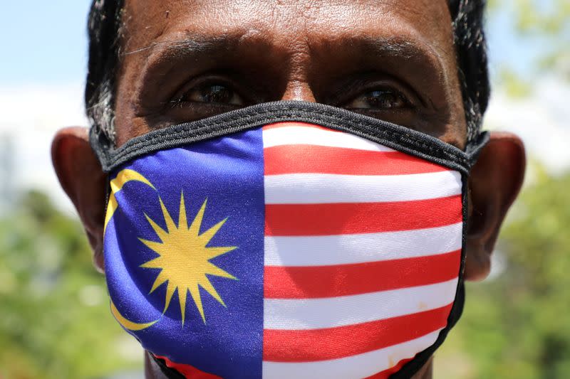 A supporter of People's Justice Party wearing Malaysia's flag mask pose for a picture outside National Palace, Kuala Lumpur