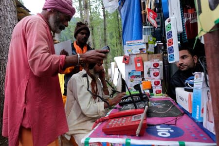 Hindu pilgrims make calls at a stall run by a Kashmiri Muslim before their journey towards the holy cave of Amarnath, at a base camp near Pahalgam