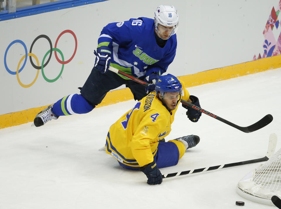 Sweden defenseman Niklas Hjalmarsson and Slovenia forward Ales Music battle for the puck in the first period of a men's quarterfinal ice hockey game at the 2014 Winter Olympics, Wednesday, Feb. 19, 2014, in Sochi, Russia. (AP Photo/Mark Humphrey)