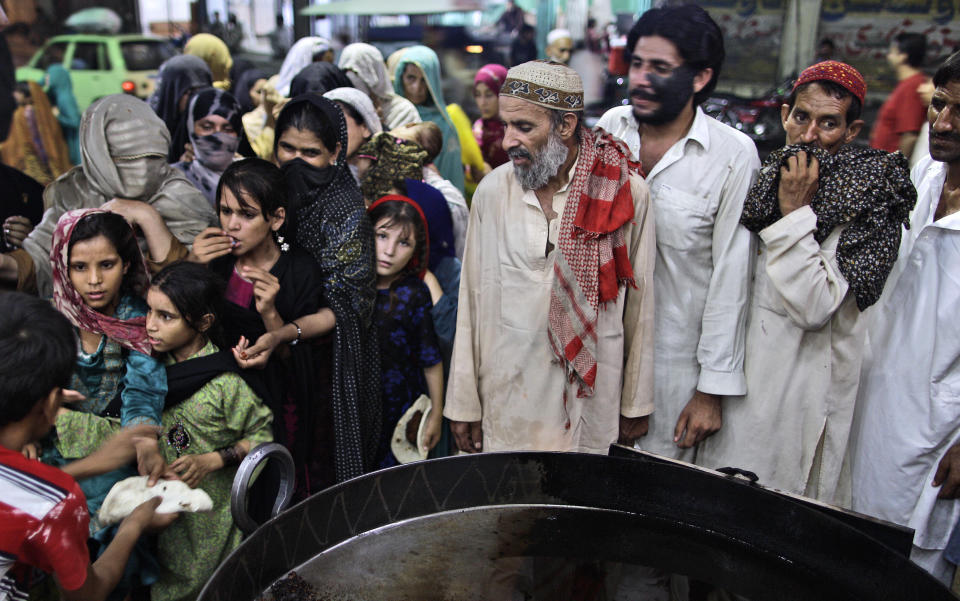 In this Tuesday, July 31, 2012 photo, Pakistanis wait to receive a donated meal during the Muslim holy fasting month of Ramadan, at a restaurant in Rawalpindi, Pakistan. For many years, Pakistan required all Sunni Muslims, who make up a majority of the country's population, to pay zakat to the government. That regulation changed recently, but many Pakistanis seem unaware and continue to pull their money out of the bank to elude the state. (AP Photo/Muhammed Muheisen)