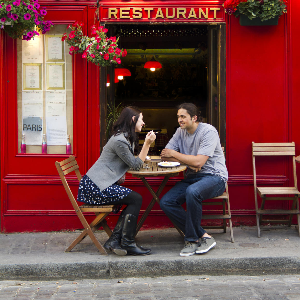 Young couple sitting in sidewalk cafe, Paris, France.