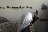 <p>A Palestinian woman gestures in front of a wall riddled with heavy machine-gun fire from an Israeli tank outside the Paradise hotel on Nativity Road in the West Bank town of Bethlehem, Oct. 29, 2001. (Photo: Jacqueline Larma/AP) </p>