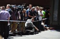 Members of the media monitor the situation near the cafe