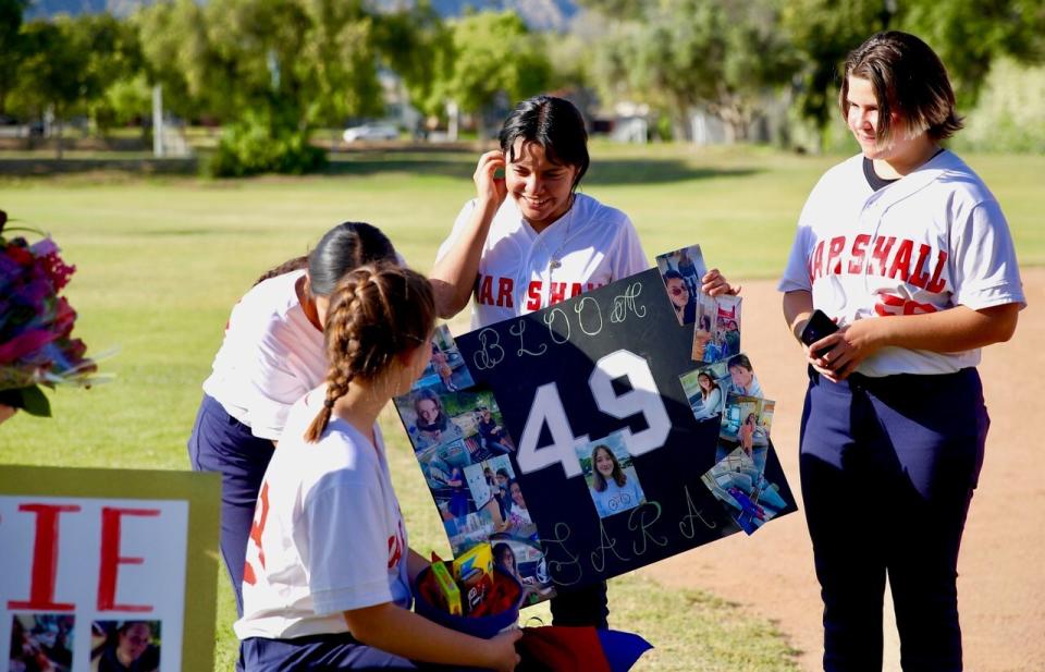 Sara Bloom is given a poster by her Marshall teammates during a ceremony to honor seniors in the program.