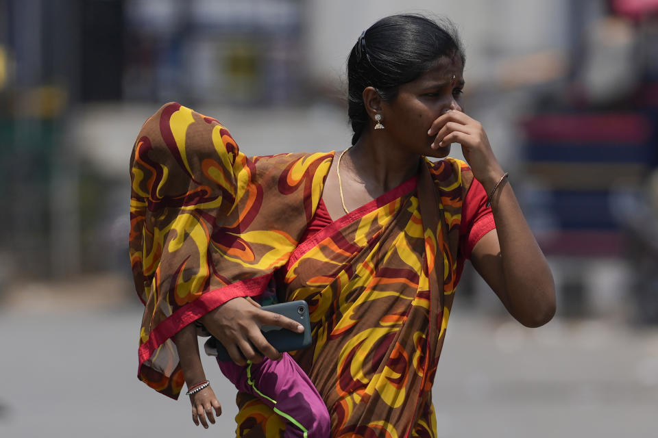A woman covers a child using a part of her sari to shield from the sun on a hot summer day in Hyderabad, India, Tuesday, April 30, 2024. (AP Photo/Mahesh Kumar A.)