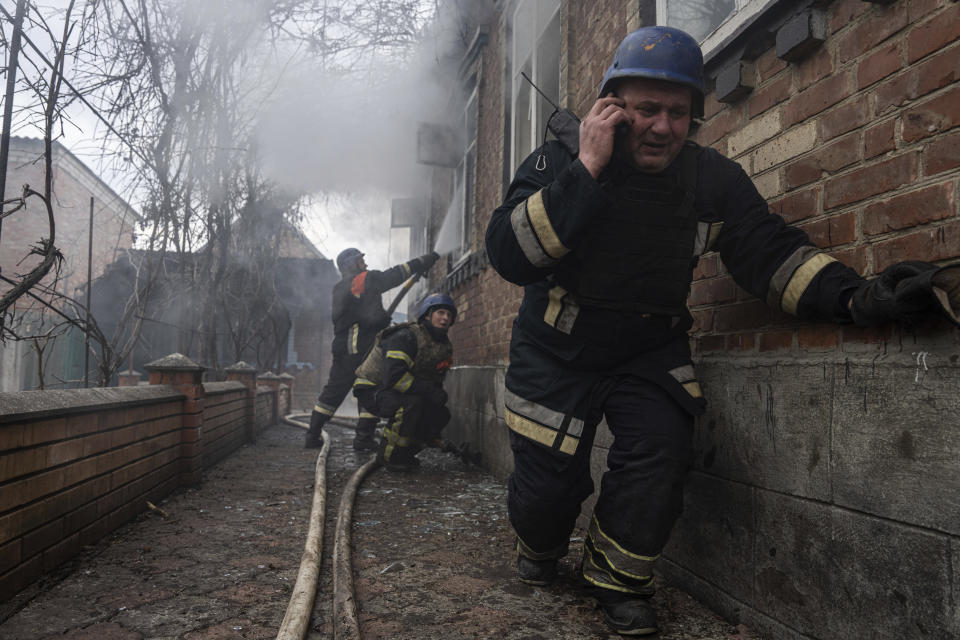 A rescue worker speaks on the phone while his team puts out a fire in a house which was shelled by Russian forces at the residential neighbourhood in Kostiantynivka, Ukraine, Friday, March 10, 2023. (AP Photo/Evgeniy Maloletka)